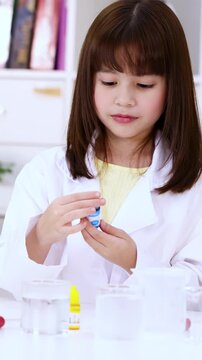 Young Girl in Lab Coat Opening Dropper Bottle for Science Experiment