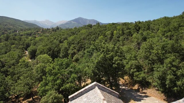 Backward reveal aerial shot of the Romanesque Chapelle de Sant Marti, an 12th-century stone church nestled in the Pyrenees mountains, Corsavy, France.