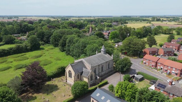 Aerial view of historic stone church surrounded by green fields and trees