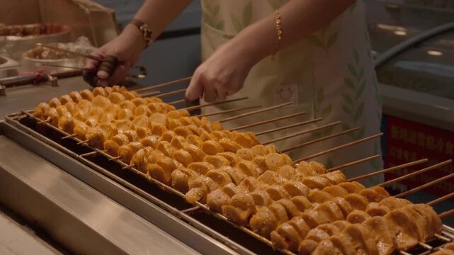 Spiced skewered gluten being grilled, with hands adjusting skewers on a commercial grill in a food stall.