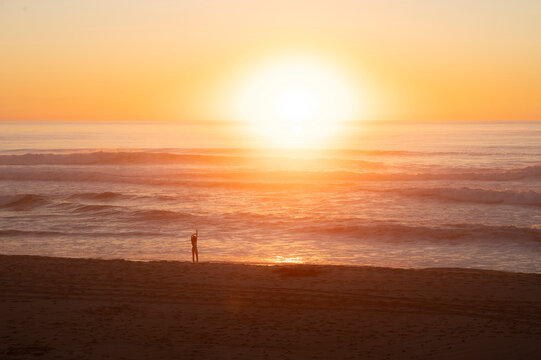 Silhouette of person stretching on beach during golden ocean sun