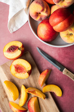 Fresh peaches and nectarines being sliced on a cutting board