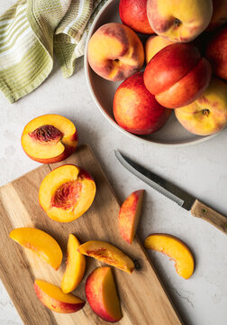 Ripe peaches and nectarines being sliced on a cutting board