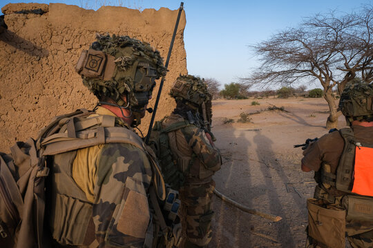 French army section working its way between the mud walls of a hamlet in the Sahel near Tin-Akoff, Burkina Faso