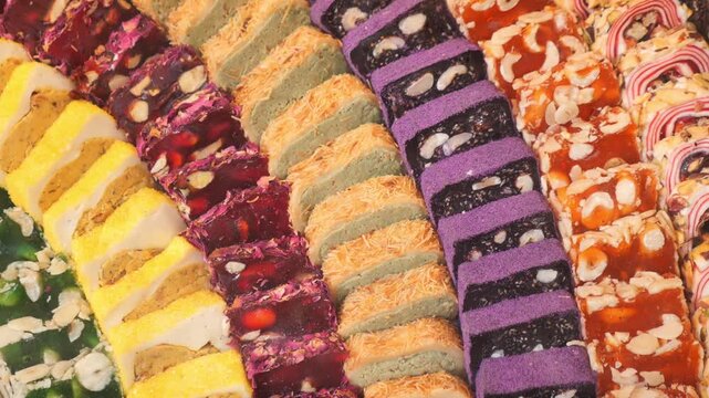 Rows of colorful turkish delight lokum with nuts and fruit flavors displayed.