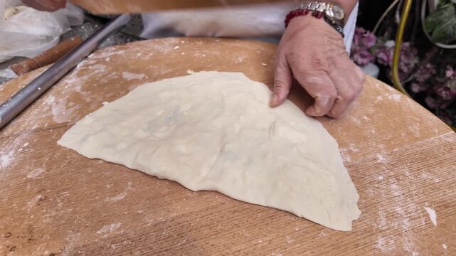 Traditional dough preparation with a wooden rolling pin for flatbread.