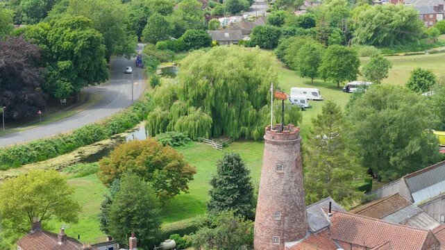 Aerial view of historic brick windmill surrounded by trees and rooftops