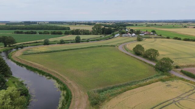 Aerial view reveals a winding river through golden green fields