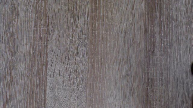 Black tape arrow on wooden floor, caucasian lighting technician arranging directional mark for cable route, careful placement and pressing, overhead studio closeup, removable