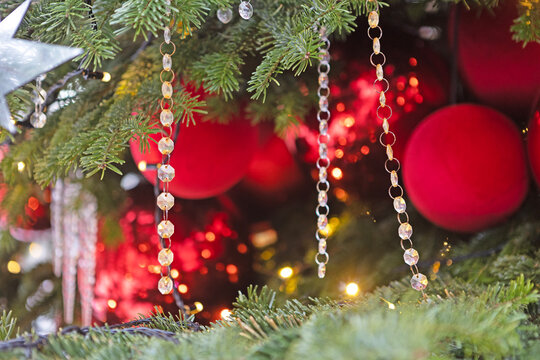 Pine branch with crystal beads. New Year's garland. Red Christmas baubles out of focus. Background for New Year's or Christmas greetings. Festive Christmas decoration. Copy space