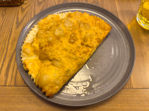 Whole fried cheburek on gray dish on table close-up