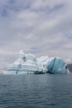 Layered iceberg with volcanic ash stripes floating in Jokulsarlon glacier lagoon, Iceland