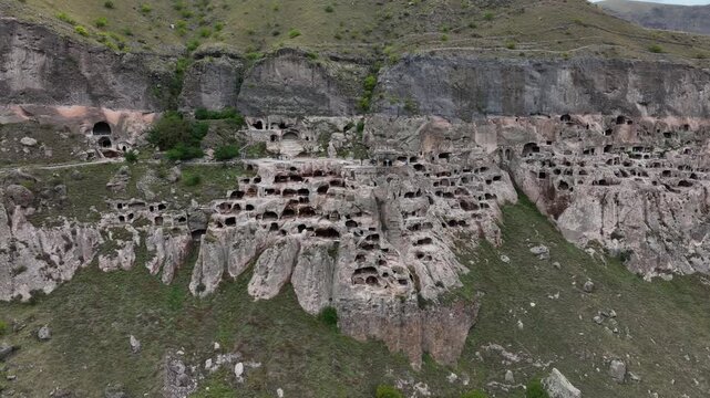 Aerial view flying towards the ancient Vardzia cave monastery complex, a historic cultural monument carved into the Erusheti mountain in southern Georgia