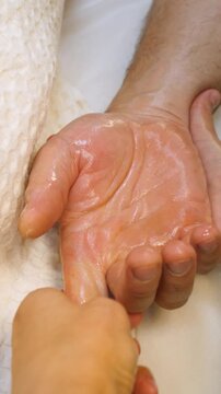 Professional female masseuse giving relaxing back massage to man in peaceful spa salon. Male guest relaxing during professional aromatherapy oil massage in modern beauty clinic - Vertical video