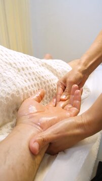 Professional female masseuse giving relaxing back massage to man in peaceful spa salon. Male guest relaxing during professional aromatherapy oil massage in modern beauty clinic - Vertical video