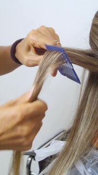Women's Hair Salon. The stylists at the women's salon are working with a young woman. Beauty salon and makeup - vertical video.
