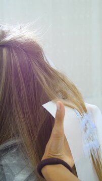 Women's Hair Salon. The stylists at the women's salon are working with a young woman. Beauty salon and makeup - vertical video.