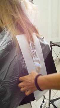 Women's Hair Salon. The stylists at the women's salon are working with a young woman. Beauty salon and makeup - vertical video.