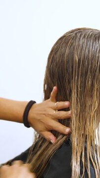 Women's Hair Salon. The stylists at the women's salon are working with a young woman. Beauty salon and makeup - vertical video.