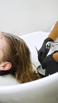 Women's Hair Salon. The stylists at the women's salon are working with a young woman. Beauty salon and makeup - vertical video.
