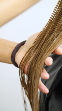 Women's Hair Salon. The stylists at the women's salon are working with a young woman. Beauty salon and makeup - vertical video.