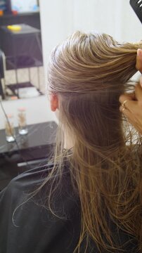 Women's Hair Salon. The stylists at the women's salon are working with a young woman. Beauty salon and makeup - vertical video.
