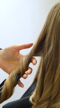 Women's Hair Salon. The stylists at the women's salon are working with a young woman. Beauty salon and makeup - vertical video.