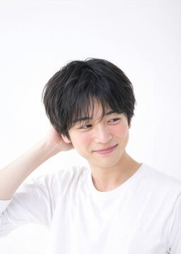 白背景で照れた笑顔を見せる20代前半の日本人男性