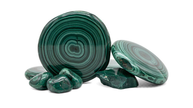 Assorted polished malachite stones and circular slices with distinct green concentric banding patterns isolated on a black background
