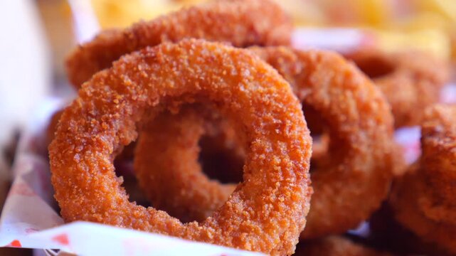 Crispy onion rings in basket, delicious fast food, appetizer, snack, motion.