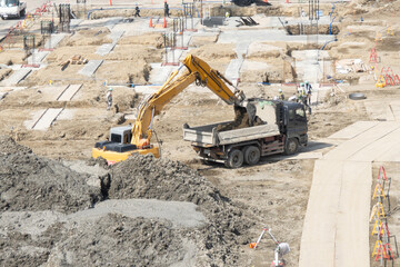 大型施設の基礎工事現場で油圧ショベルがダンプトラックに掘削土を積み込む作業 © tadashiyuki