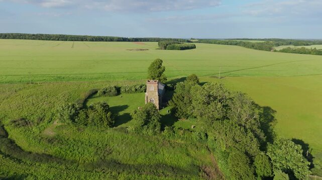 Ancient stone tower stands tall amid green fields. Chapel