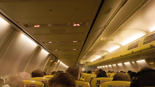 Wide view inside an airplane cabin during flight with rows of passengers seated in their places capturing an authentic atmosphere of commercial air travel and aviation