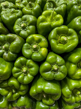 Bright green bell peppers filling the frame with their vibrant color and fresh texture, showcasing healthy organic produce available for cooking - stock photo