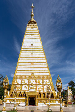 Tall white and gold pagoda at Wat Phra That Nong Bua with blue sky in Ubon Ratchathani Thailand