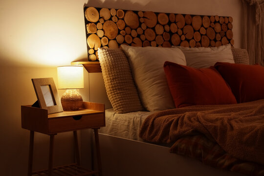 Cozy bedroom interior, relaxation and sleep hygiene with warm ambient lighting and rustic wooden headboard in a modern home