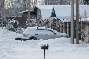 Obraz premium Snow covers a parked car and surrounding yard