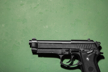 Fototapeta premium Gun violence and crime prevention, black semi-automatic pistol on a textured green background for law enforcement and security industry concepts