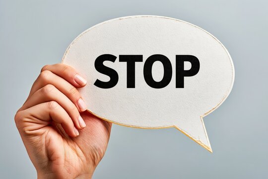 Hand holding speech bubble with stop text sign and warning concept