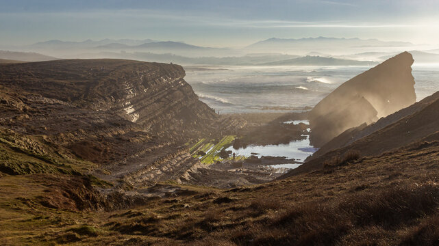 Misty coastal cliffs with tide pool and sea at Liencres, Cantabria
