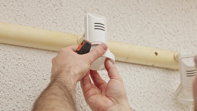 Man installing an electrical wall fixture with a screwdriver indoors