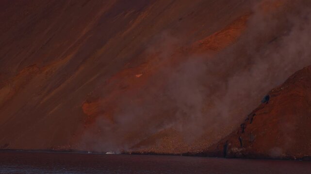 Dramatic slow motion footage captures a large rock tumbling down Stromboli&rsquo;s volcanic slope, sending a billow of dust into the air as it crashes into the tranquil sea under soft, evening light.