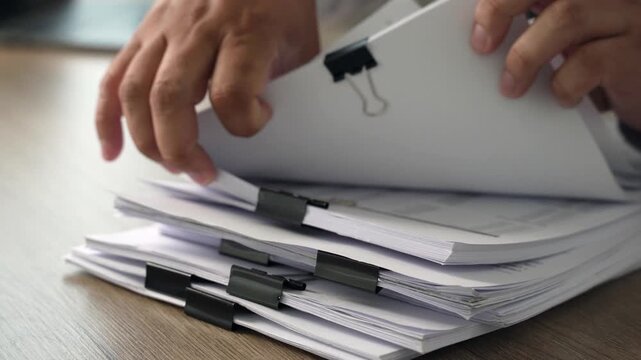 Hands organizing stacked documents beside a stethoscope, showing healthcare document management, medical records organization and clinical administration.