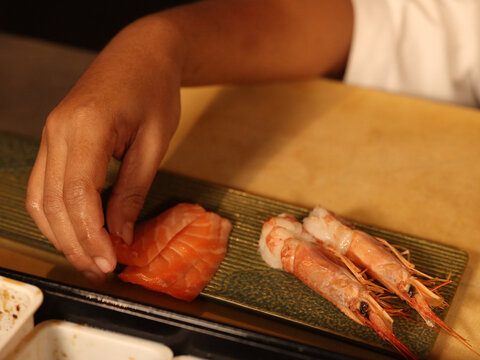 Chef Plating Fresh Salmon Sashimi and Raw Prawns on Ceramic Dish
