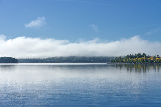 Serene Nordic Lake with Low Fog Rolling Over Boreal Forest in Autumn