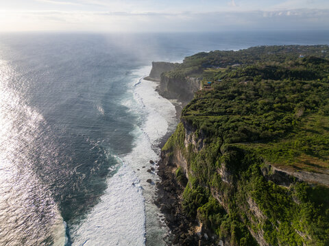 Aerial View of Uluwatu Cliffs and Waves, Bali: Aerial view of steep green limestone cliffs and white waves rolling along the coast near Uluwatu on the Bukit Peninsula in Bali, Indonesia