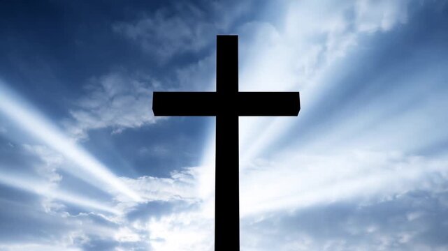 Slow pan tracking shot of silhouetted cross standing and backlit by sun rays breaking through clouds in blue sky outdoor morning spiritual scene