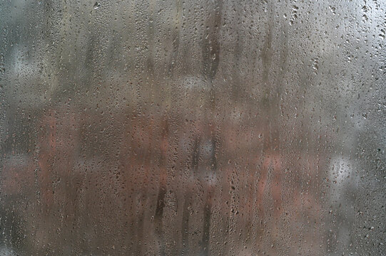 Moisture beads run down fogged glass. Transparent water droplets form natural pattern on window pane inside house. Dampness problem causes steam effect on cold surface. wet glass, abstract background