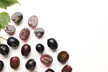Naklejka premium Fresh ripe grapes and green leaves on white background, flat lay. Space for text