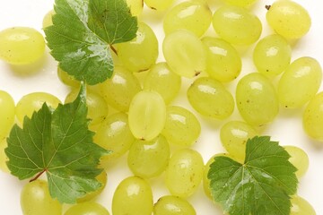 Naklejka premium Fresh ripe grapes and green leaves on white background, top view